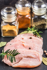Raw turkey breast slices with spices on table.