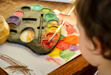 Little girl painting with water color - top view