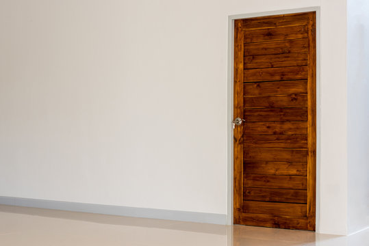 Wooden door set in a white wall