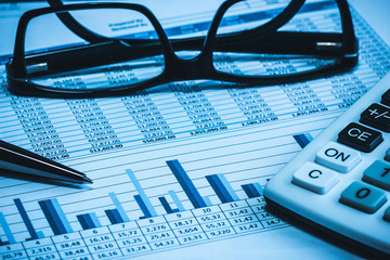 Accounting financial bank banking account stock spreadsheet data with glasses pen and calculator in blue 
