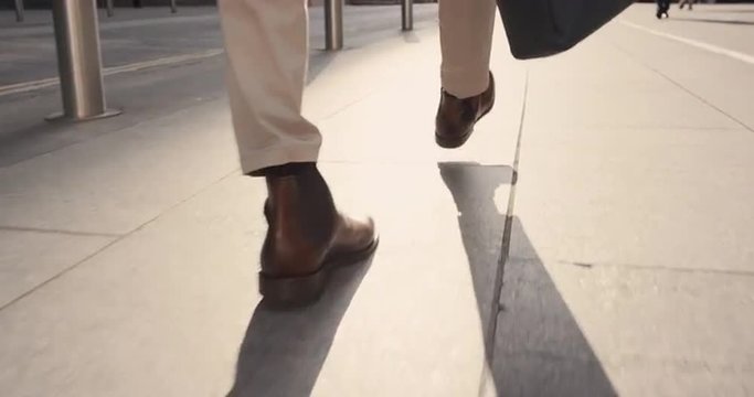 Close crop of businessman feet walking in city