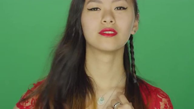 Young Asian woman staring and being flirty, on a green screen studio background