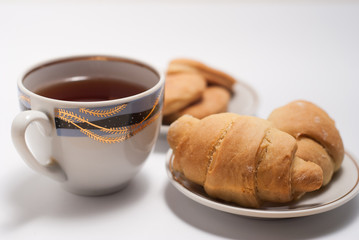 Cup of tea with pattern and fresh croissants
