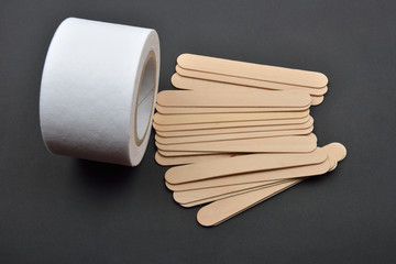 Picture of many wooden spatulas and roll of paper for wax depila