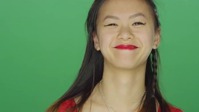 Young Asian woman smiling and dancing, on a green screen studio background