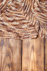 Knitted scarf on old wooden burned table or board for background