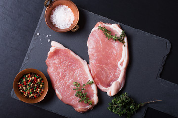 Fresh meat steaks on black slate background