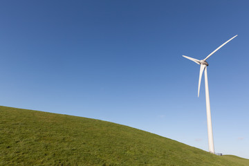 Obraz premium Close up of wind turine on a grass field with a clear blue sky