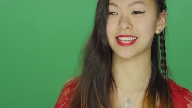 Young Asian woman smiling and dancing, on a green screen studio background