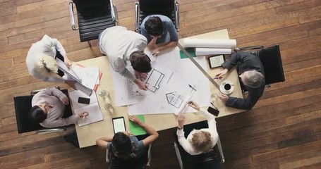Top View of Business people meeting around boardroom table discussing architectural plans for new sustainable shared office space - Powered by Adobe