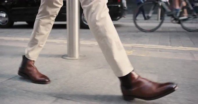 Close crop of businessman feet walking in city