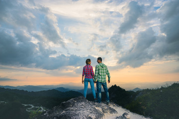 Fototapeta premium Couple on the top of mountain with beautiful sunset background. Back view.