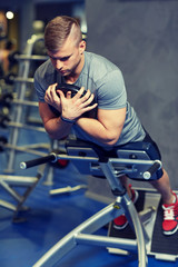 young man flexing back muscles on bench in gym