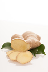 Ginger root with green leaves isolated over white.