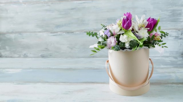 Beautiful summer bouquet of flowers in the hat box on the vintage blue wooden background 