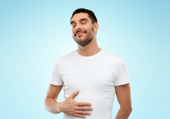 happy full man touching tummy over blue background