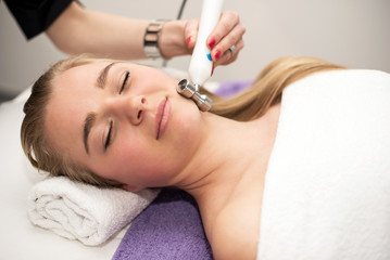 Naklejka premium Young woman lying on massage table receiving face massage. Beaut