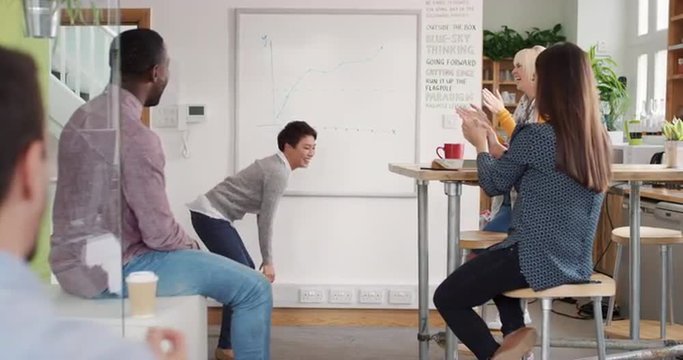 Crazy happy Asian business woman dancing doing victory dance in team meeting celebrating success achievement smacking booty
