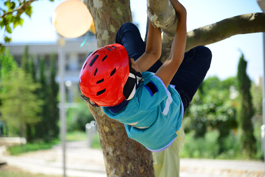 Bopy with red helmet climbing a tree