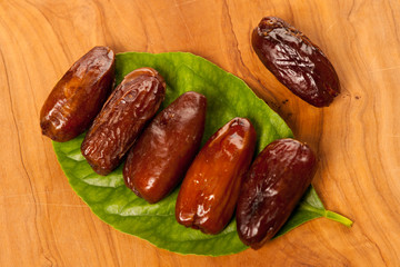 Sweet dried dates fruit on green leaf, mediterranean desert on w