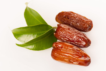Sweet dried dates fruit on green leaf, mediterranean desert isol