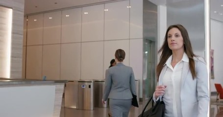 Attractive successful businesswoman leaving corporate office lobby checking smartwatch