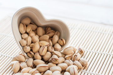 Pistachios in ceramic bowl on wooden table