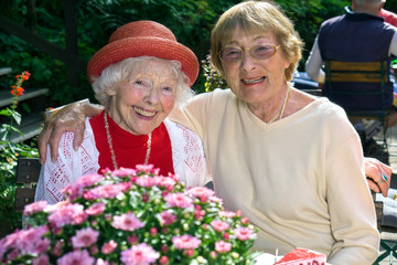 Two affectionate senior women enjoying coffee.