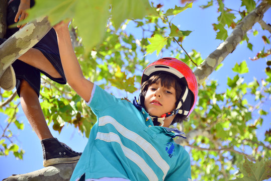 Bopy with red helmet climbing a tree