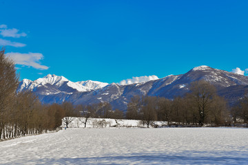 Fototapeta na wymiar Veduta invernale con neve e montagne innevate 