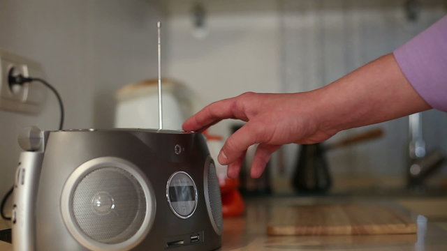 Human hand switching on radio in the kitchen