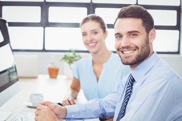 Confident business people sitting at computer desk