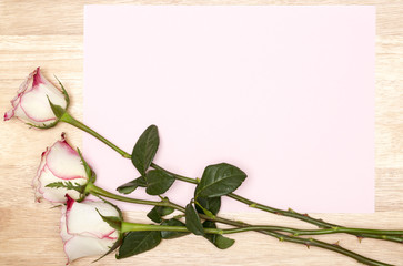 Blank card with white rose on a wooden background. Copy space