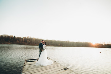 Elegant beautiful wedding couple posing near a lake at sunset