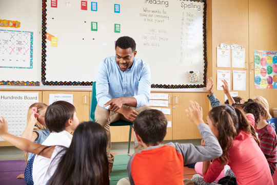 Elementary school kids sitting around teacher in a classroom