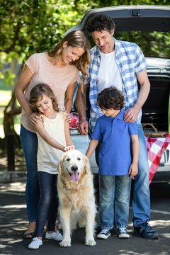 Smiling Family Standing In Front Of A Car