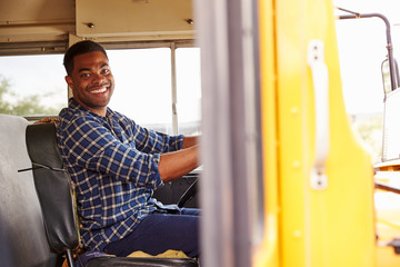 Smiling school bus driver sitting in bus - obrazy, fototapety, plakaty
