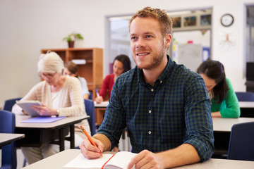Young man looking up at the board at adult education class