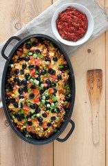 tortilla chips nachos with melted cheese, shredded chicken, green onions, tomato, black olives, corn and salsa.