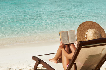 Young woman reading a book at beach - 104939942