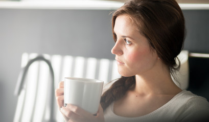 Woman with cup of coffee or tea in kitchen