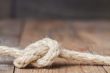 Old frayed rope twisted and tied in a bundle on a rough wooden background