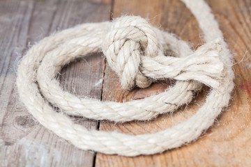 Old frayed rope twisted and tied in a bundle on a rough wooden background