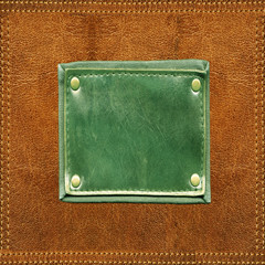 Fototapeta premium Green blank leather label stitched onto orange leather surface