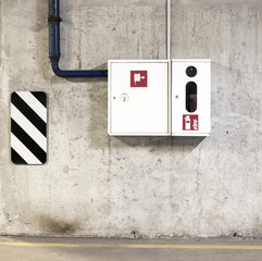 A fire extinguisher and a fire-hose in the white box on concrete wall