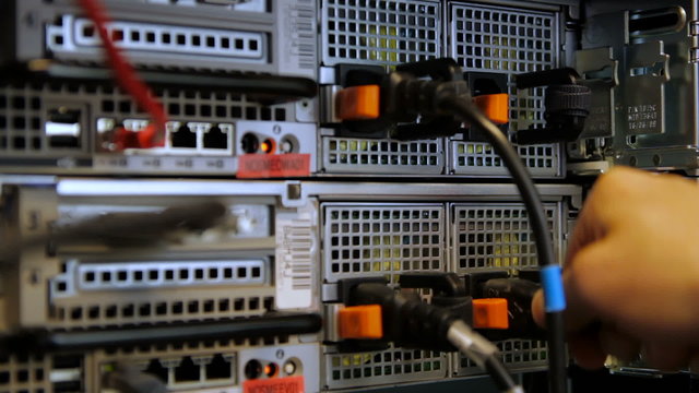 IT technician inserts power cord in server