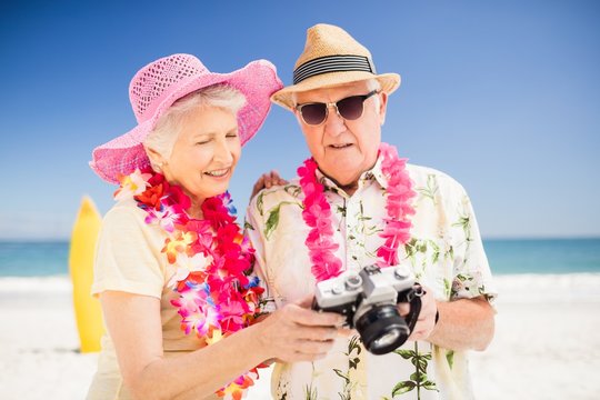 Senior couple holding camera on the beach