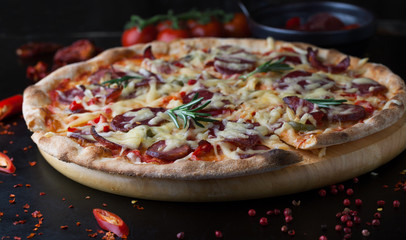 Delicious pizza with salami, tomatoes and hot peppers