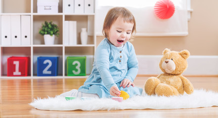 Toddler girl have tea with her teddy bear