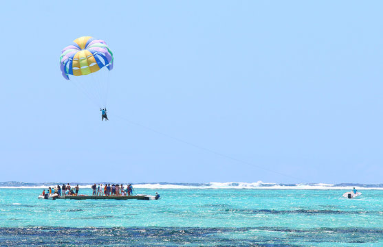 Parasailing over Indian Ocean near Mauritius Island. Happy holidays on the beach.